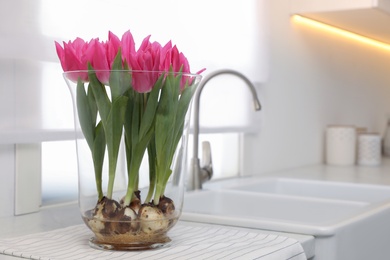 Photo of Bouquet of beautiful tulips with bulbs on countertop in kitchen. Space for text