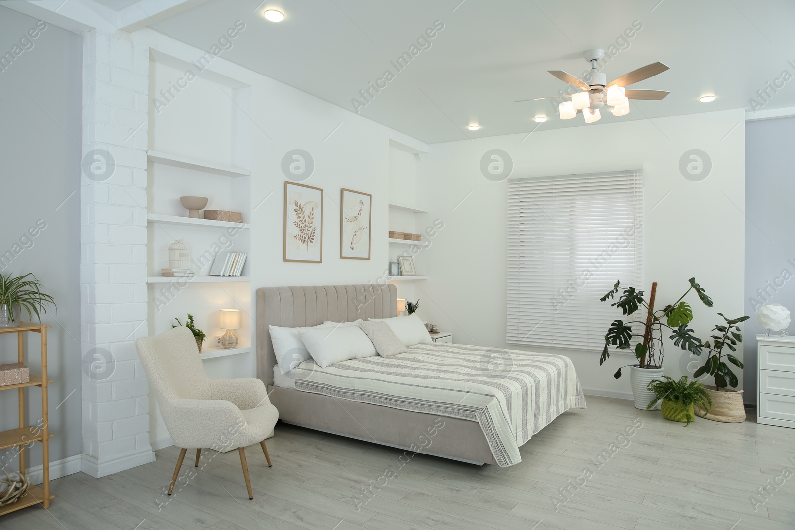 Photo of Comfortable furniture, ceiling fan, houseplants and accessories in stylish bedroom