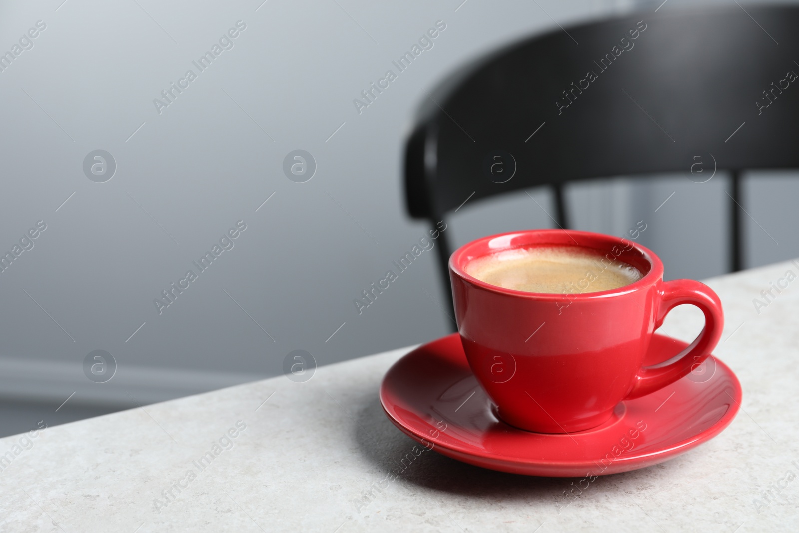 Photo of Red ceramic cup with hot aromatic coffee on white table indoors, space for text