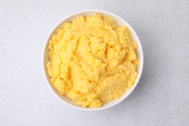 Photo of Tasty cornmeal in bowl on light gray table, top view