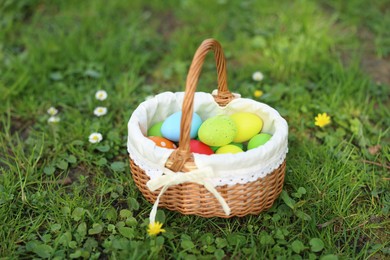 Easter celebration. Painted eggs in wicker basket on green grass