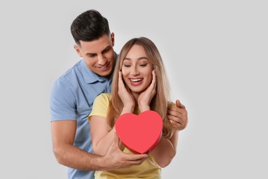 Photo of Man surprising his girlfriend with gift on grey background. Valentine's day celebration