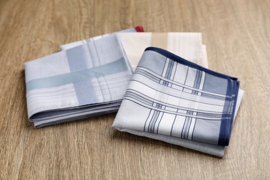 Photo of New handkerchiefs on wooden table. Stylish accessory