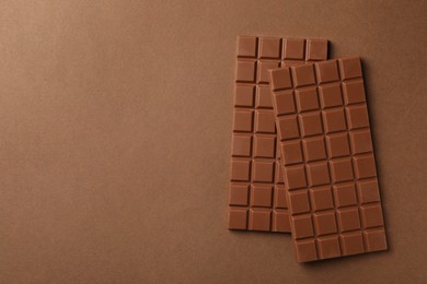 Tasty chocolate bars on brown background, flat lay. Space for text