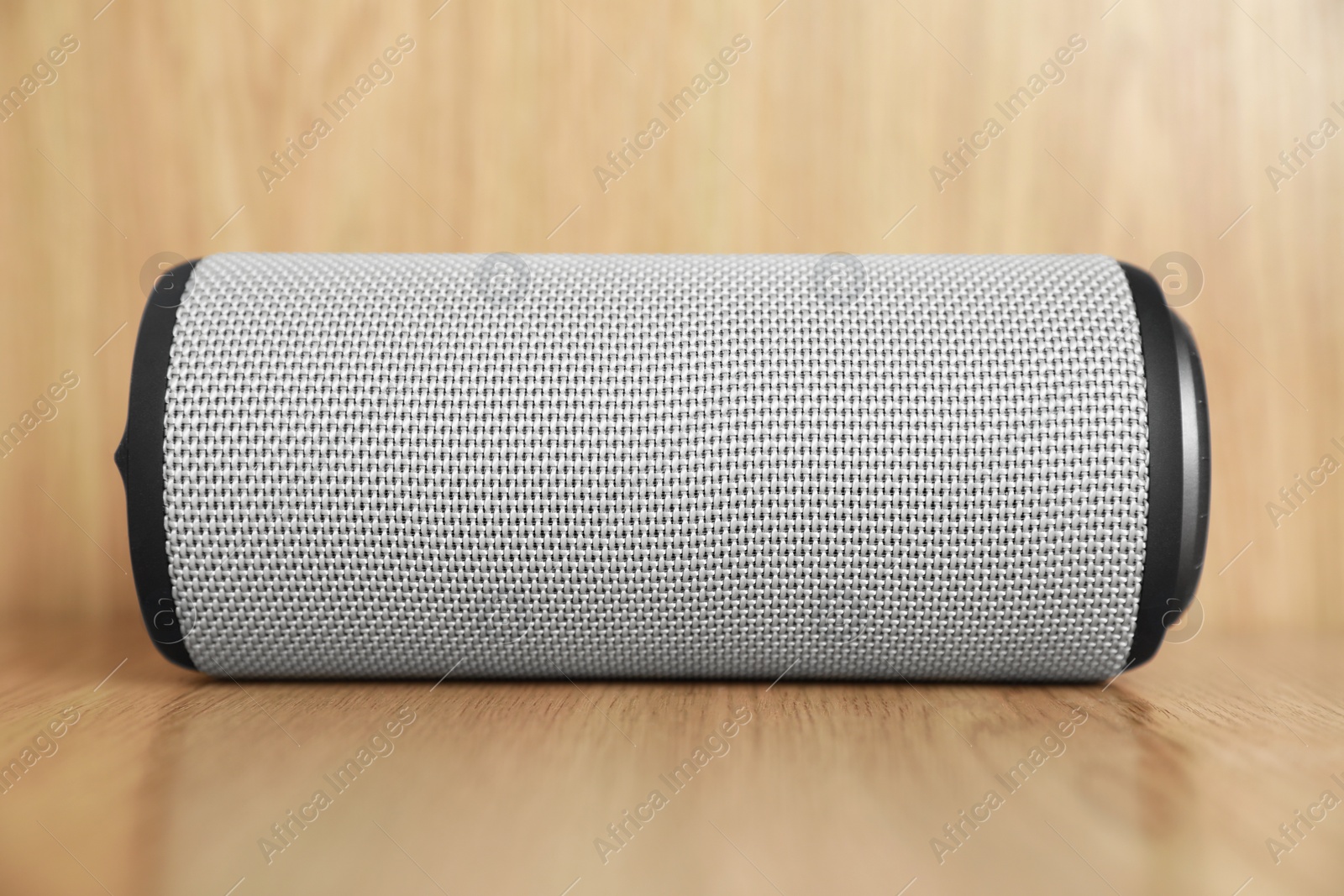 Photo of One portable bluetooth speaker on wooden table, closeup. Audio equipment