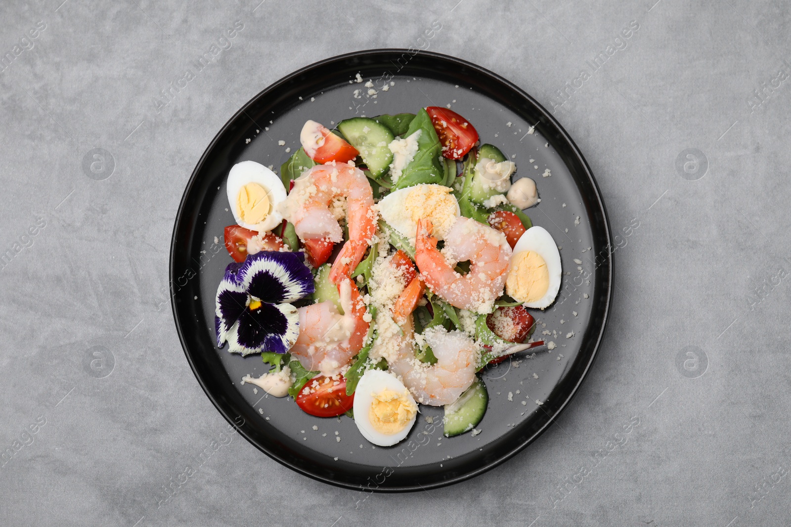 Photo of Delicious Caesar salad with shrimps on grey table, top view