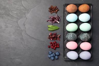 Naturally painted Easter eggs and space for text on black table, flat lay. Coffee beans, red cabbage, spinach, hibiscus, cranberries, blueberries used for coloring