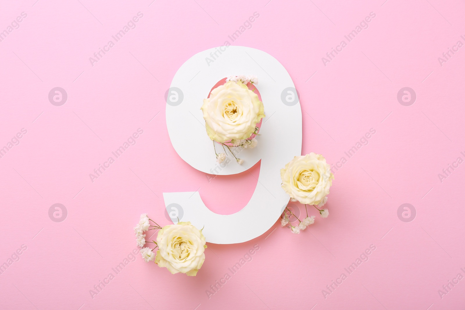 Photo of Paper number 9 and beautiful flowers on pink background, top view