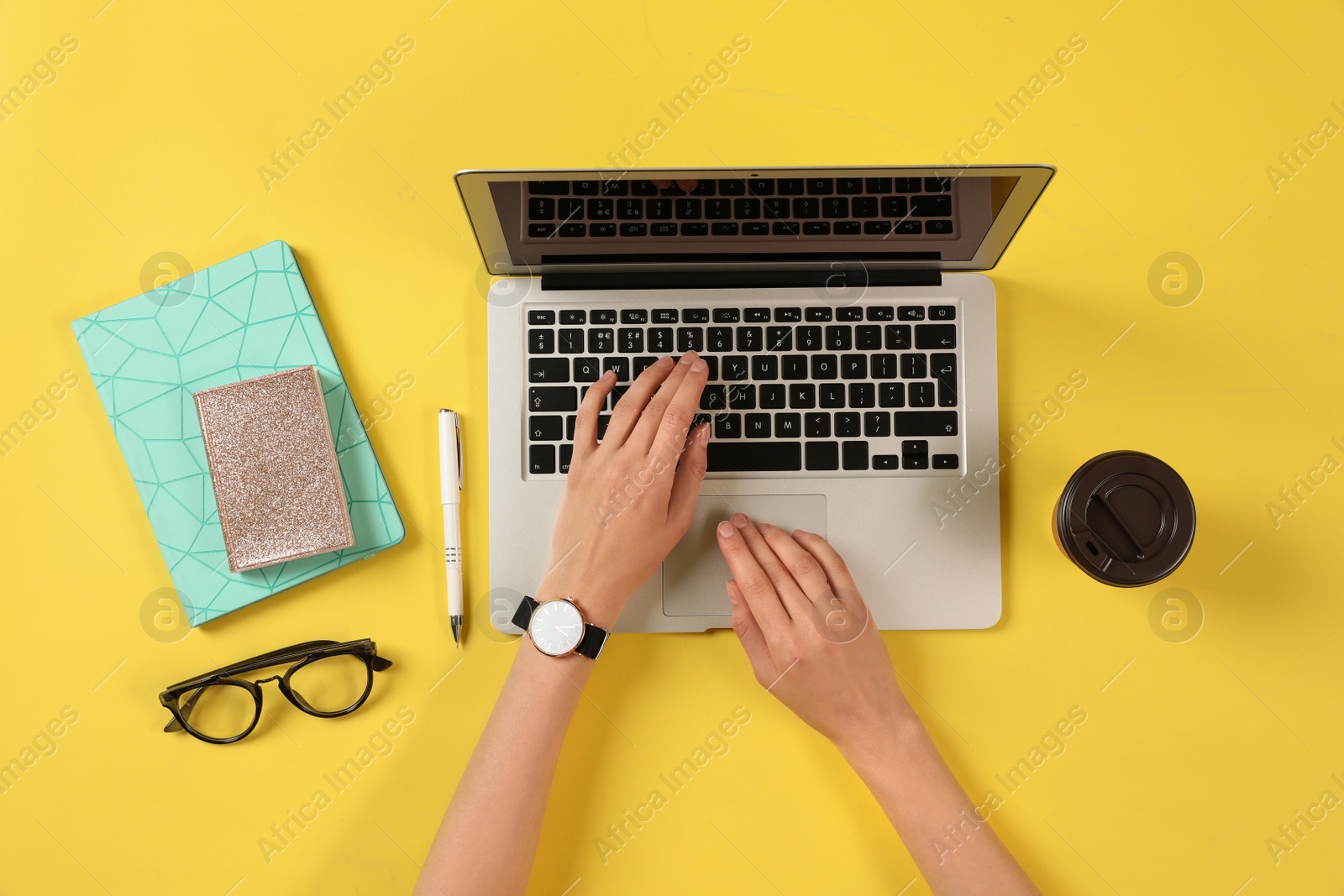 Photo of Woman using modern laptop at color table, top view