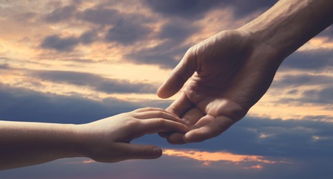 Image of Godparent with child and beautiful sky with clouds at sunset on background, closeup