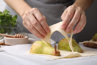 Woman making pastry with dough and fresh pears at white table, closeup