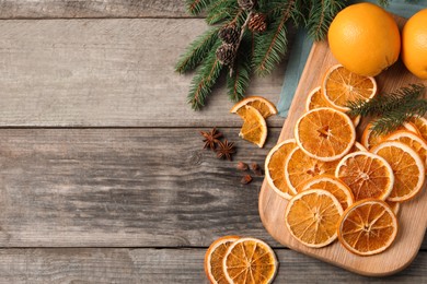 Dry orange slices, anise stars and fir tree branches on wooden table, flat lay. Space for text