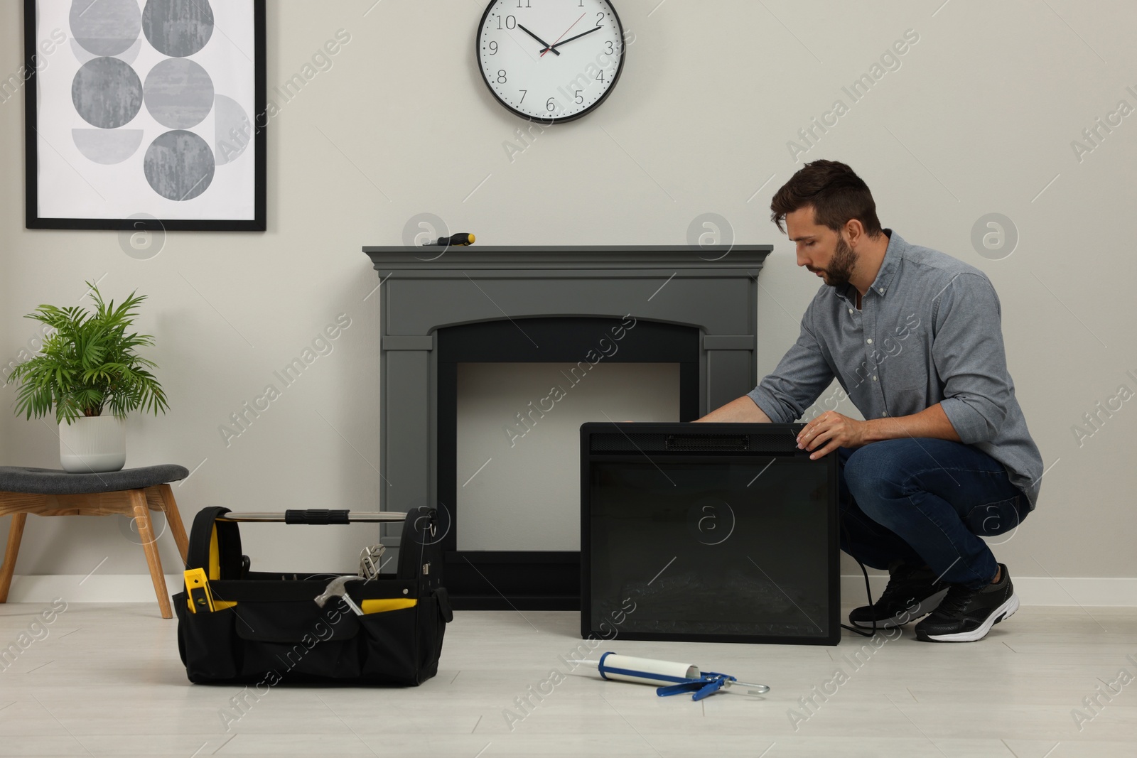 Photo of Man installing electric fireplace near wall in room