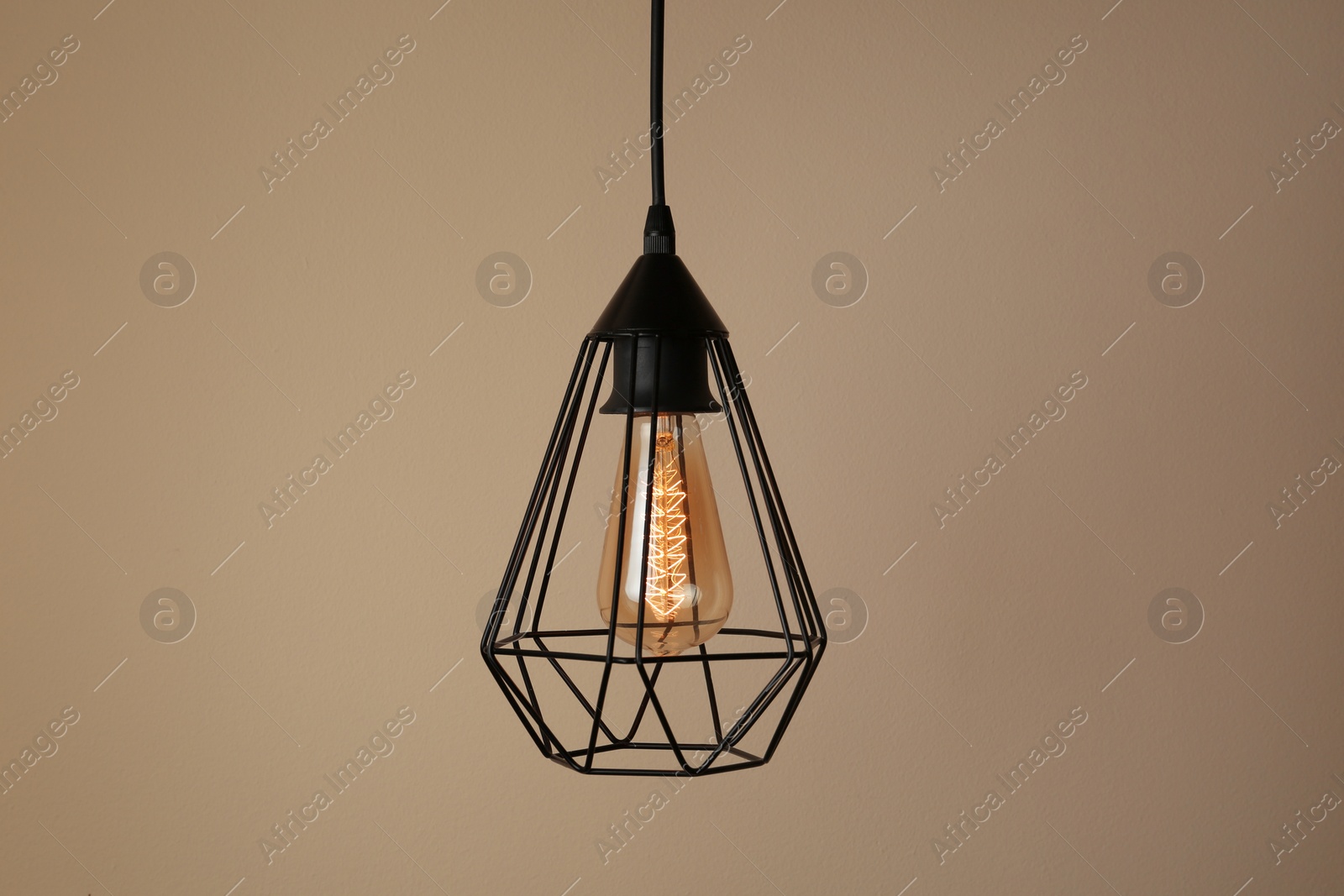 Photo of Hanging lamp bulb in chandelier against beige background