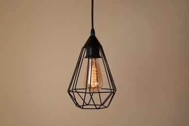 Hanging lamp bulb in chandelier against beige background