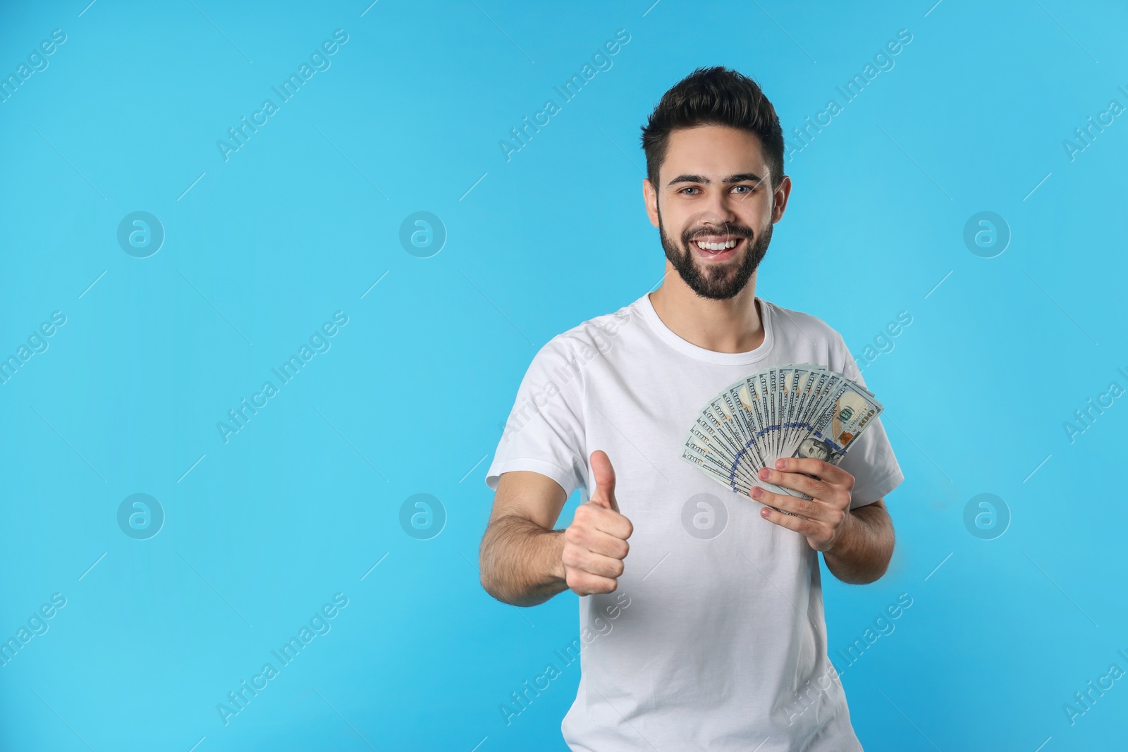 Photo of Portrait of happy young man with money on color background. Space for text