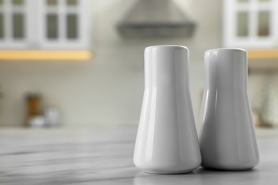 Photo of Ceramic salt and pepper shakers on white marble table in kitchen. Space for text