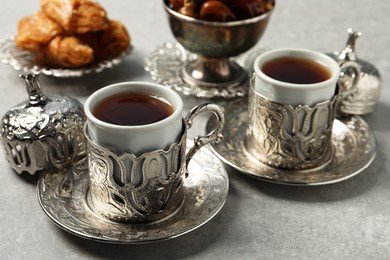 Tea, baklava dessert and date fruits served in vintage tea set on grey table