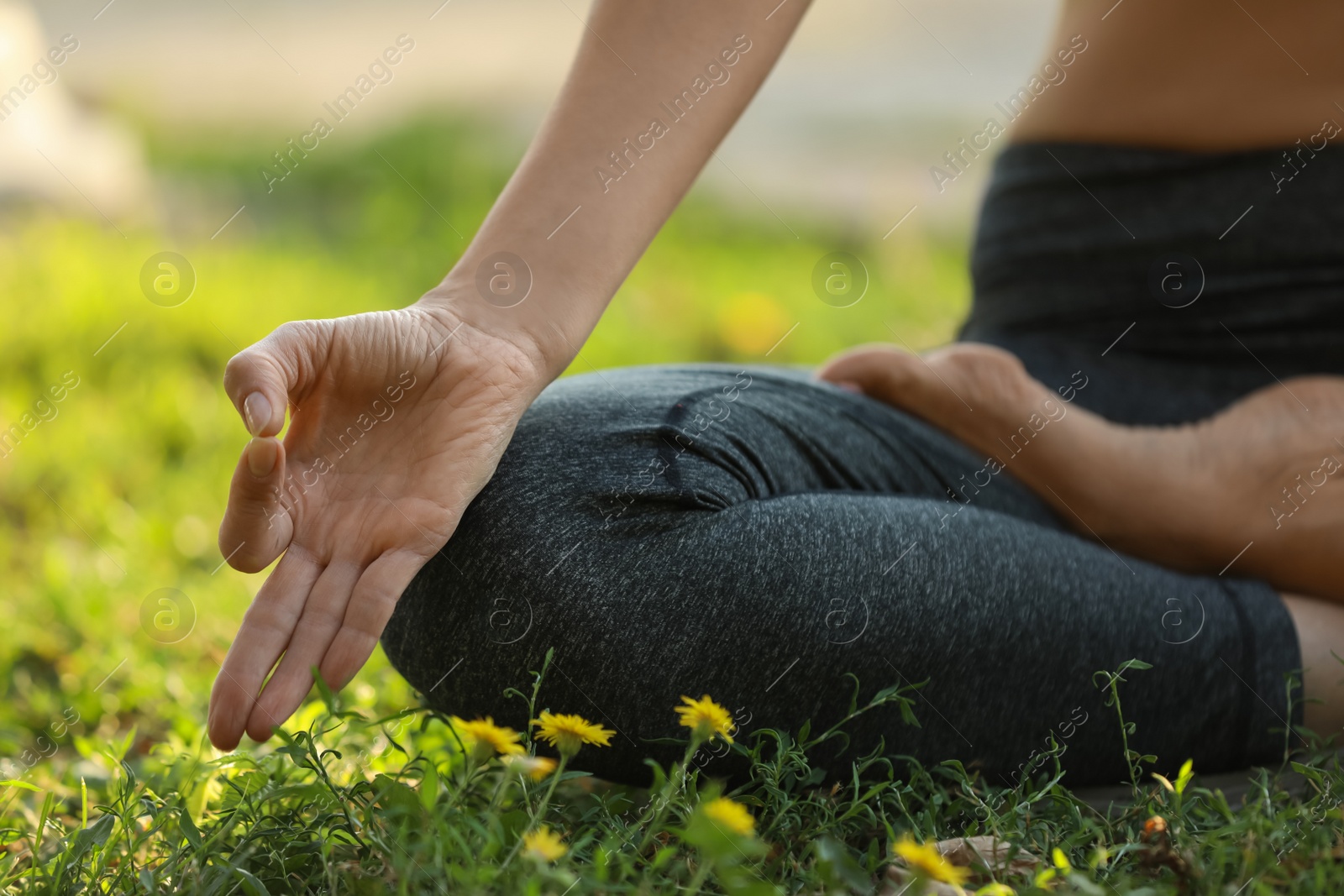 Photo of Woman meditating on green grass, closeup view