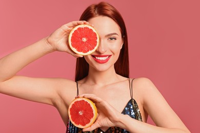 Happy woman with red dyed hair and grapefruits on pink background