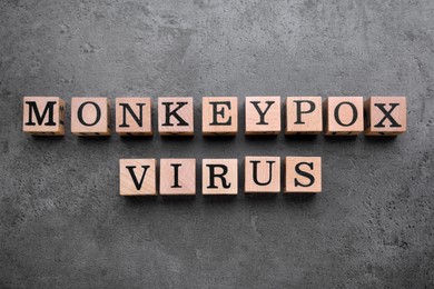 Words Monkeypox Virus made of wooden cubes on grey table, flat lay