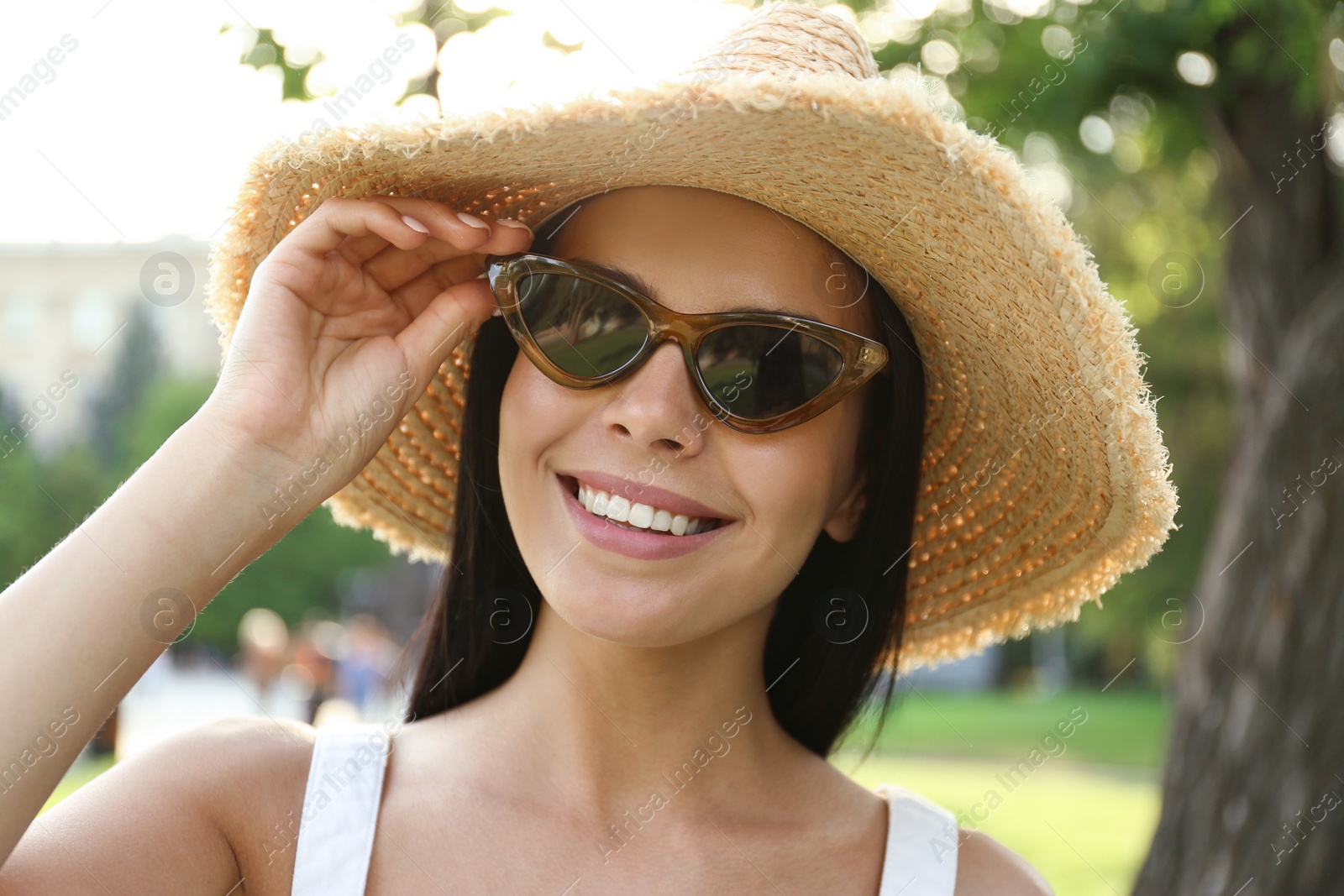 Photo of Beautiful young woman wearing stylish sunglasses in park