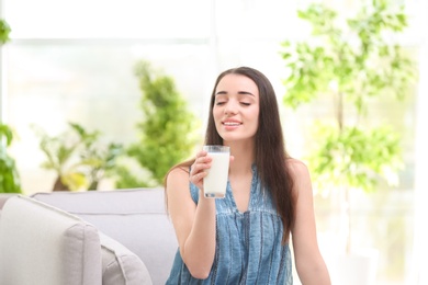 Photo of Beautiful young woman drinking milk at home
