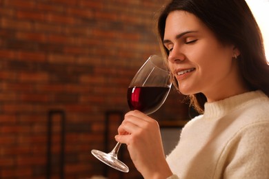 Young woman with glass of wine relaxing at home. Space for text