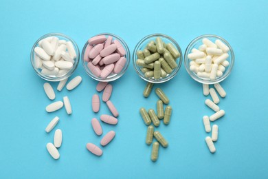 Photo of Different vitamin pills on light blue background, flat lay