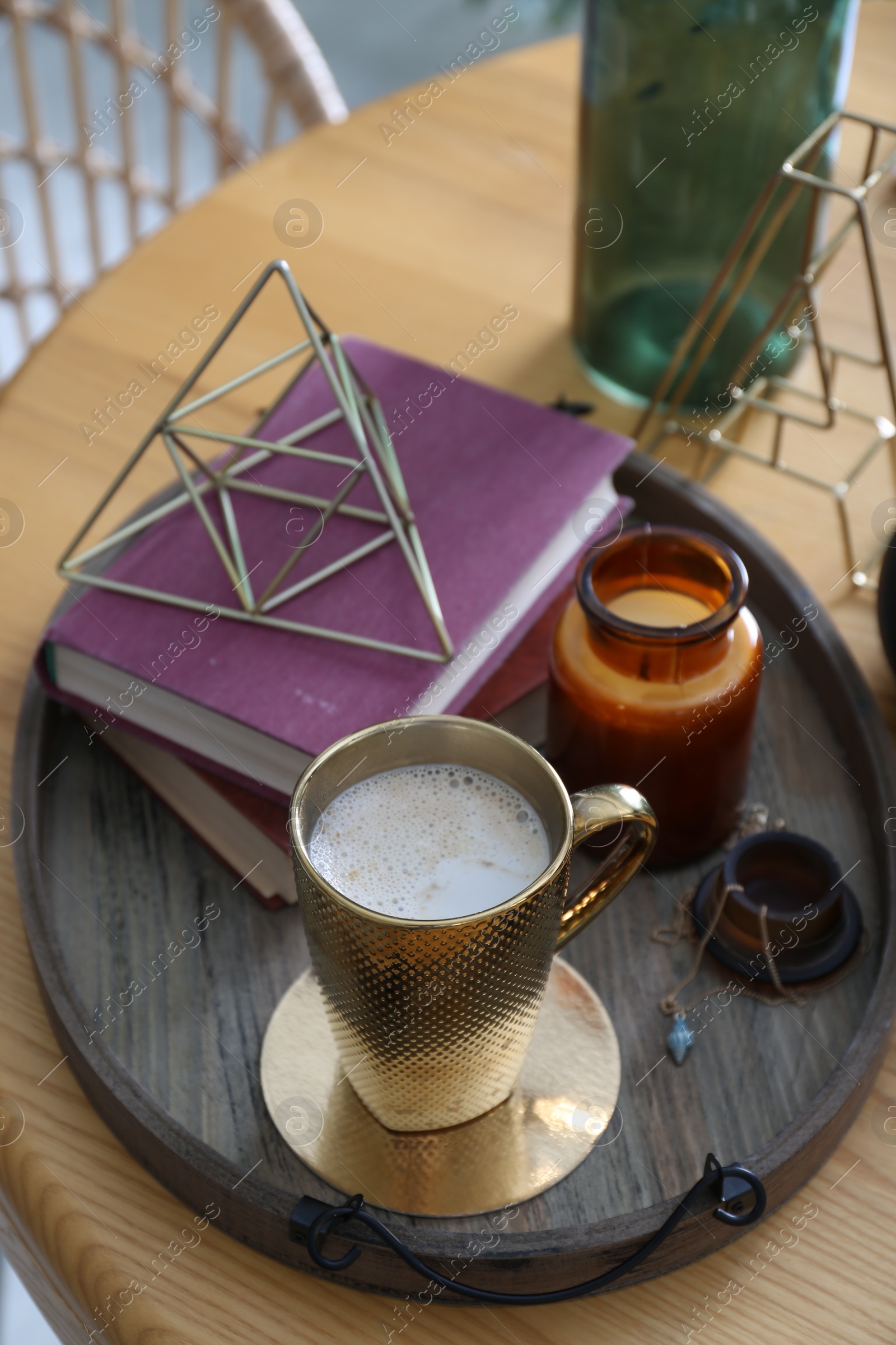 Photo of Wooden tray with decorations, books and hot drink on table indoors