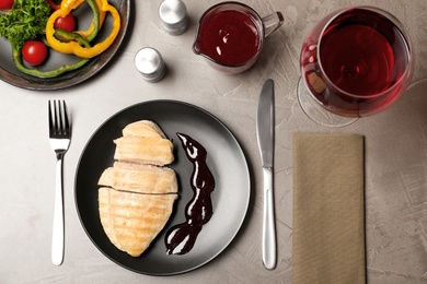 Photo of Chicken meat served with garnish, sauce and wine on grey background, flat lay