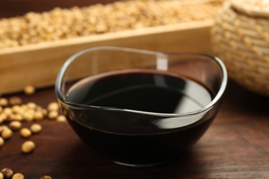 Photo of Soy sauce in bowl on wooden table, closeup