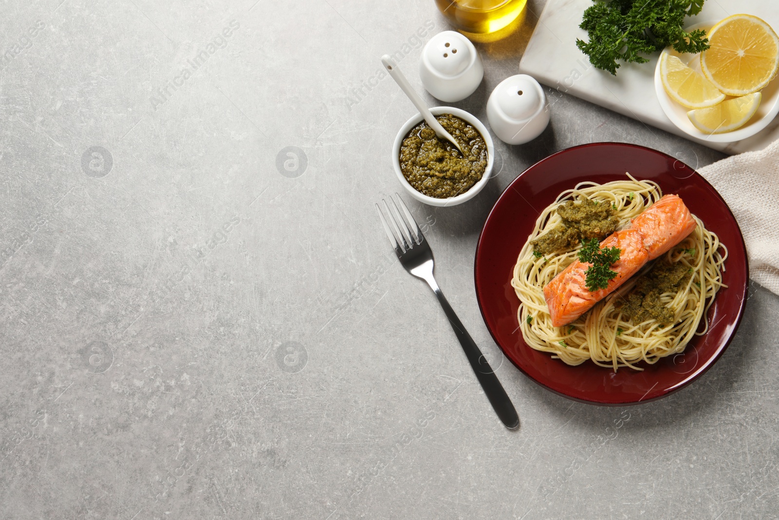 Photo of Delicious spaghetti with salmon and pesto sauce on light grey table, flat lay. Space for text