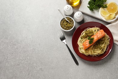 Delicious spaghetti with salmon and pesto sauce on light grey table, flat lay. Space for text