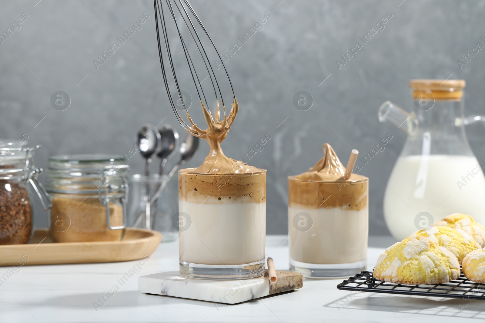 Photo of Putting cream for dalgona coffee into glass on white table