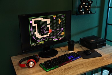 Modern computer, RGB keyboard and headphones on wooden table indoors