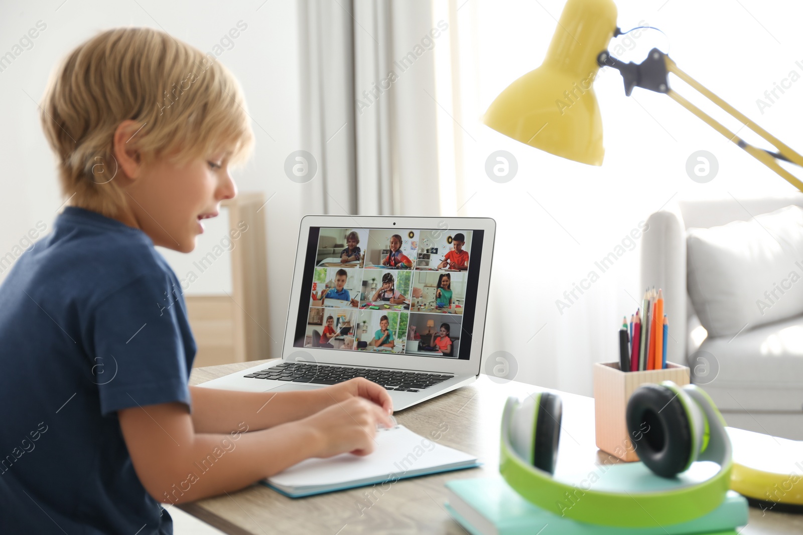 Photo of Little boy studying with classmates via video conference at home. Distance learning during COVID-19 pandemic