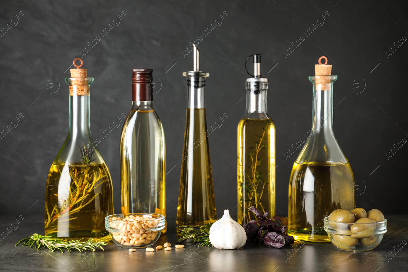 Photo of Composition with different sorts of cooking oil on grey table