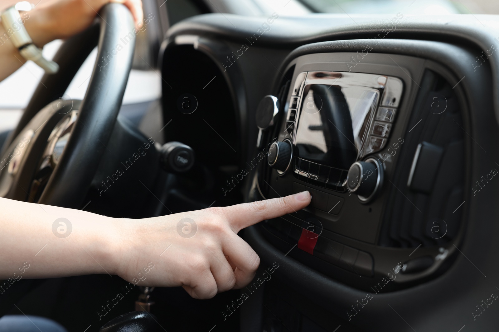 Photo of Choosing favorite radio. Woman pressing button on vehicle audio in car, closeup