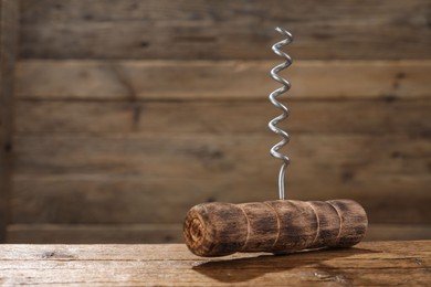 Photo of One corkscrew on wooden table, closeup. Space for text