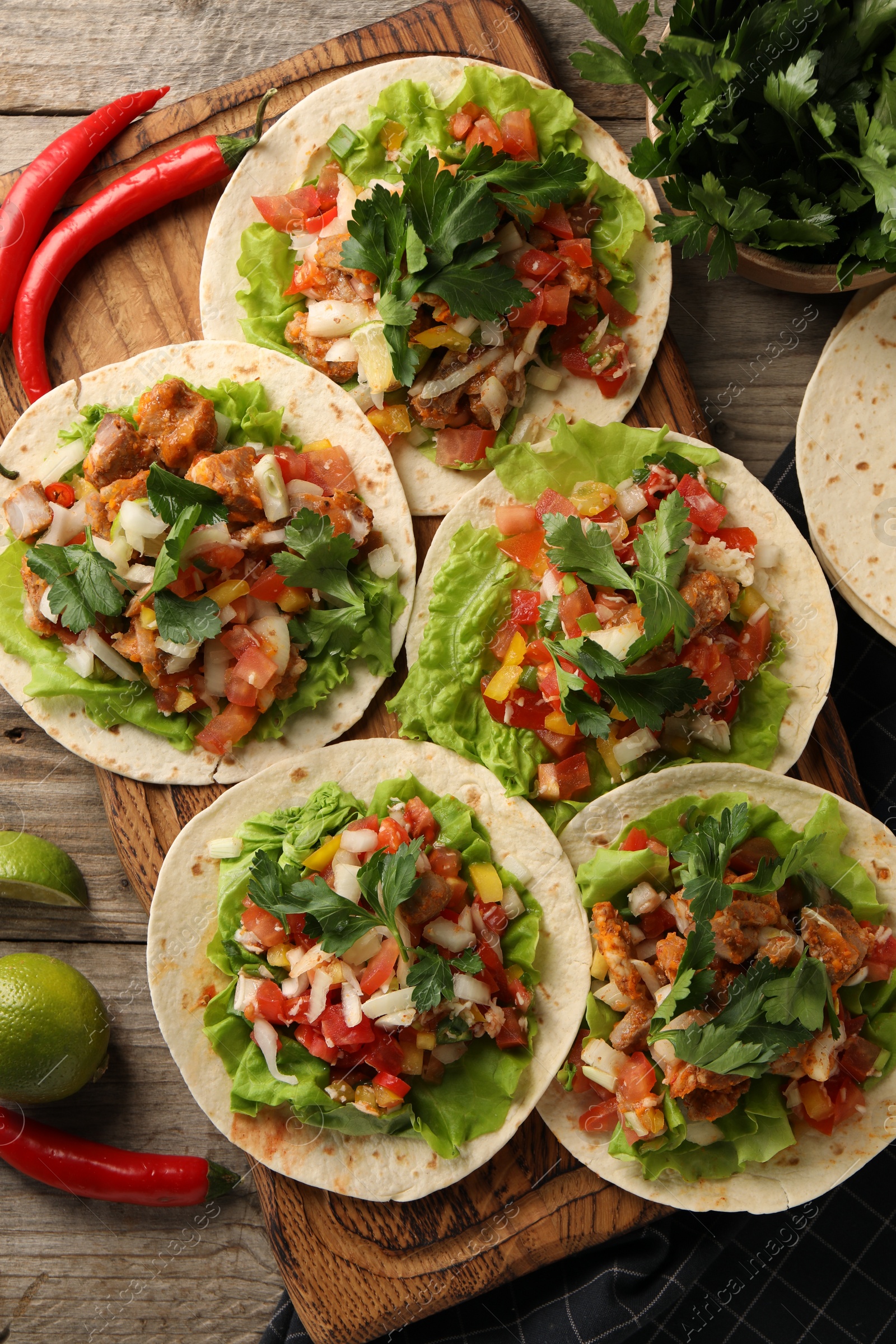 Photo of Delicious tacos with vegetables and meat on wooden table, flat lay