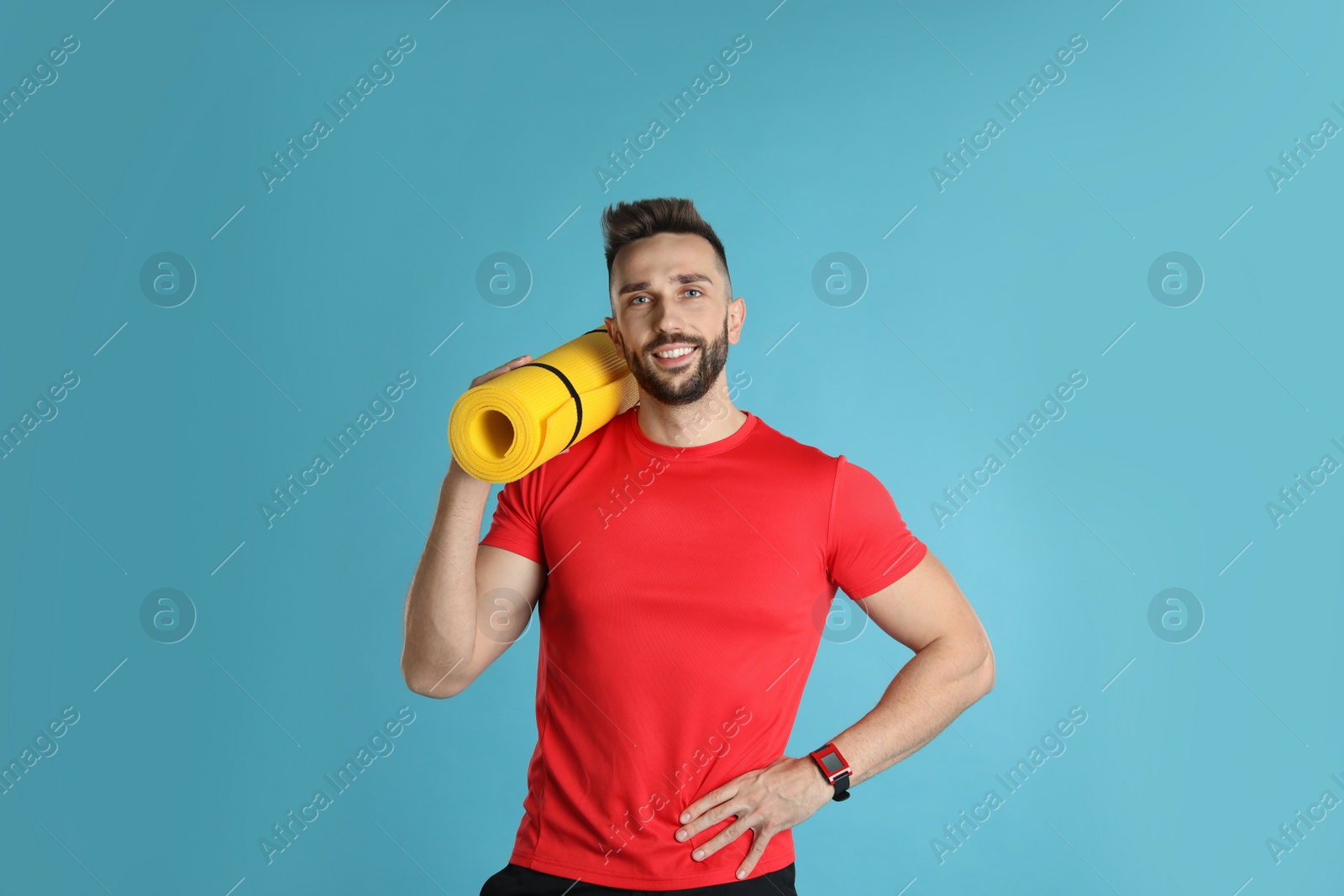 Photo of Handsome man with yoga mat on turquoise background