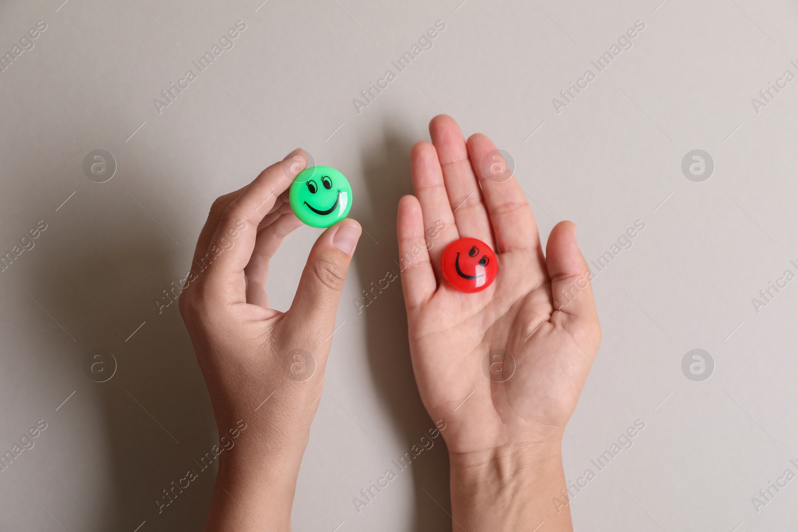 Photo of Choice concept. Woman holding magnets with happy emoticons on light background, closeup