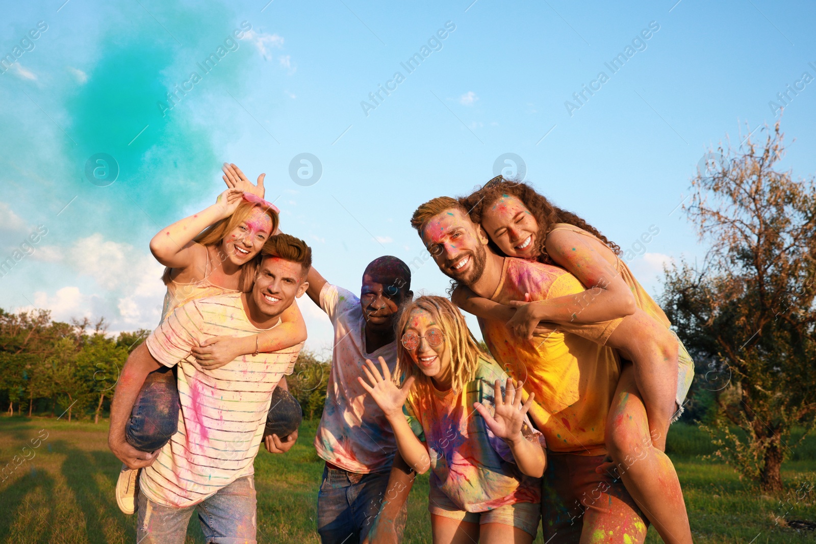 Photo of Happy friends covered with colorful powder dyes outdoors. Holi festival celebration