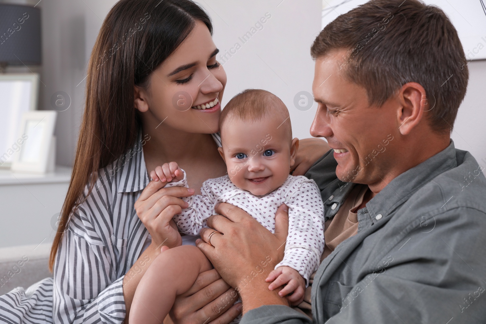 Photo of Happy family with their cute baby at home