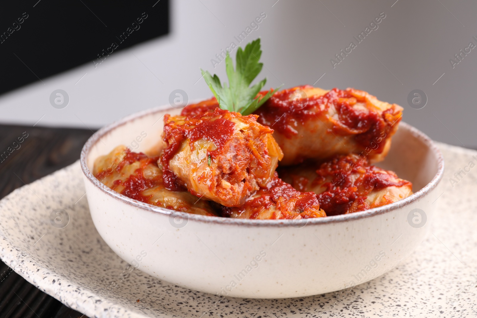 Photo of Delicious stuffed cabbage rolls cooked with homemade tomato sauce on table, closeup