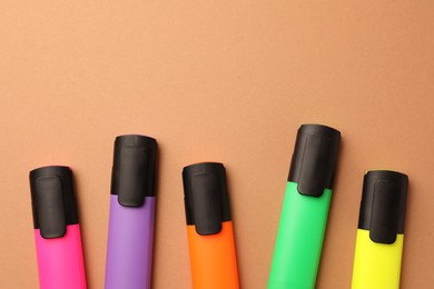 Photo of Bright color markers on pale orange background, flat lay. Space for text