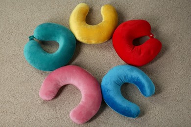 Photo of Colorful travel pillows on beige rug, top view. Space for text