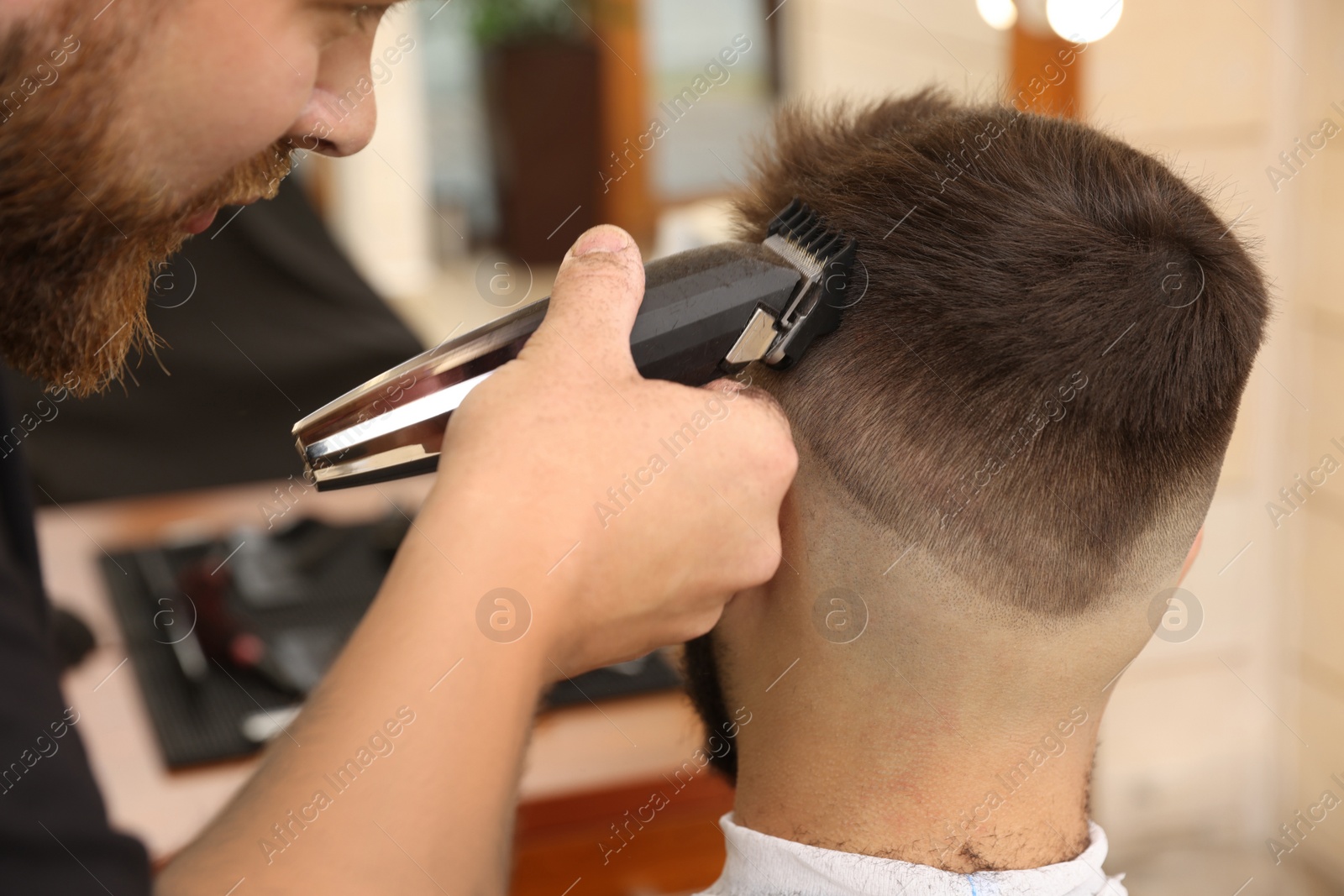 Photo of Professional hairdresser working with client in barbershop, closeup