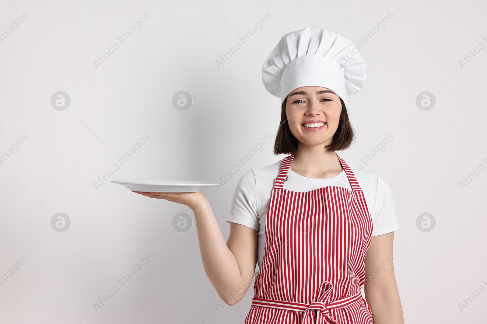 Photo of Happy confectioner with plate on light grey background